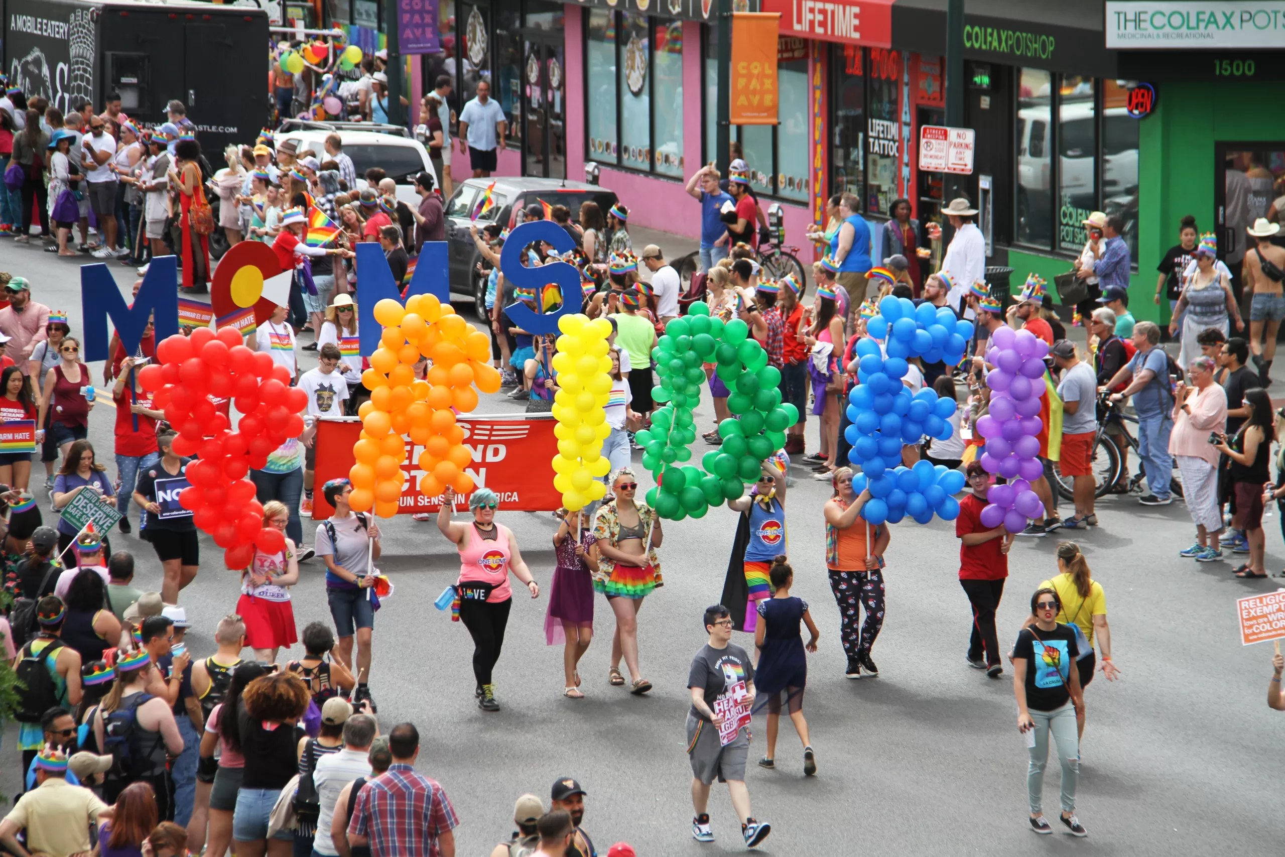 gay pride parade with balloons that say pride in rainbow letters